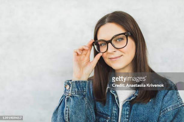 beautiful woman wearing eyeglasses against grey wall. - astigmatism stock-fotos und bilder