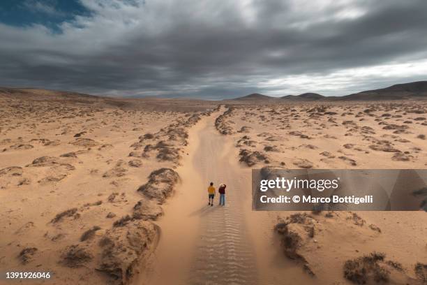 two people standing on a desert road. aerial view. - majestoso - fotografias e filmes do acervo