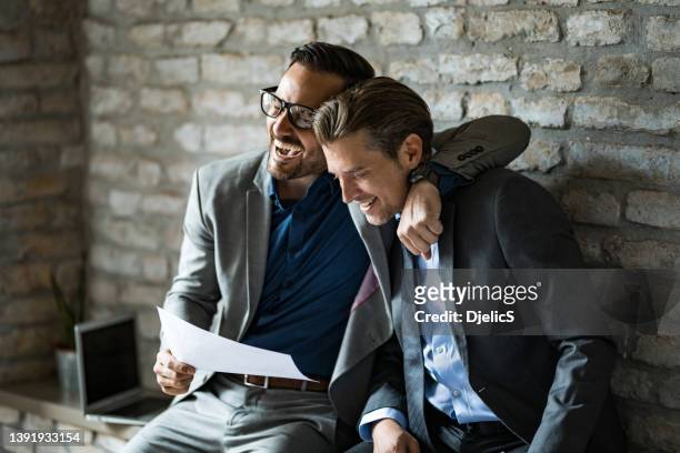 two happy businessmen laughing together in office after seeing great results. - happy laugh stockfoto's en -beelden