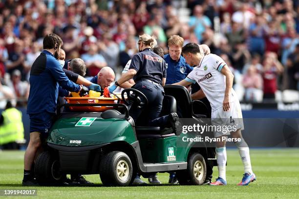 Jack Cork of Burnley interacts with Ashley Westwood of Burnley while being taken off on a stretcher during the Premier League match between West Ham...
