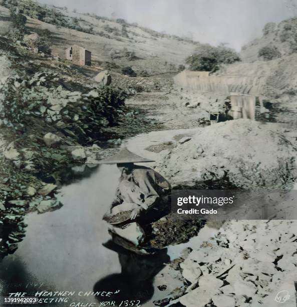 Gold prospector of Chinese descent pans for gold during the California Gold Rush, with text reading The Heathen Chinee prospecting, 1852. Note: Image...