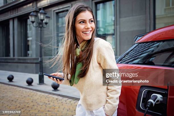 portrait of woman charging her electric car - electric car home stock pictures, royalty-free photos & images