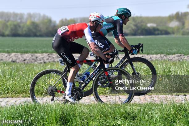 Kenneth Vanbilsen of Belgium and Team Cofidis and Marco Haller of Austria and Team Bora - Hansgrohe compete passing through a cobblestones sector...
