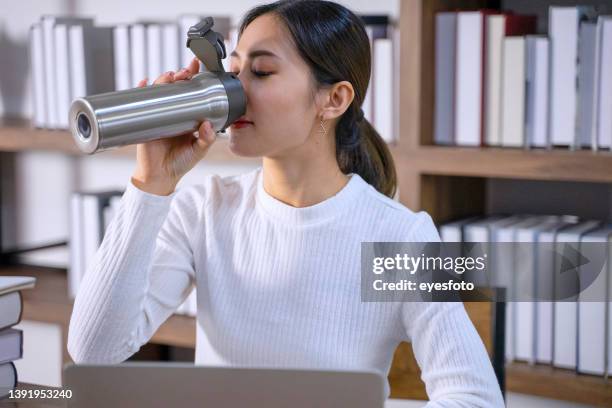 employee is drinking water via reuse bottle. - reusable water bottle office stock pictures, royalty-free photos & images