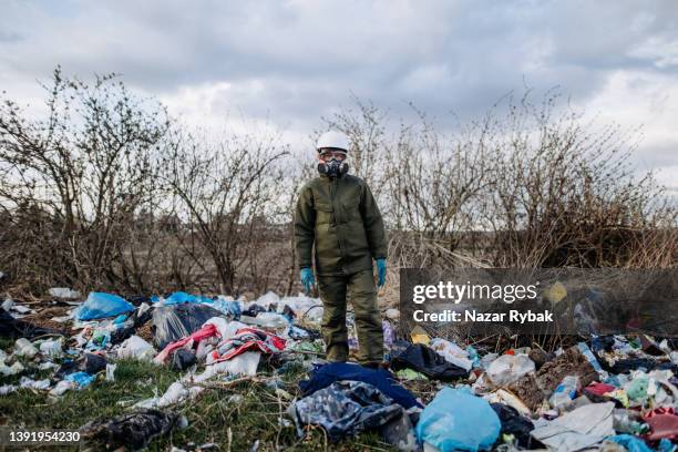 the woman in a protective suit standing among a rubbish - clothes landfill bildbanksfoton och bilder