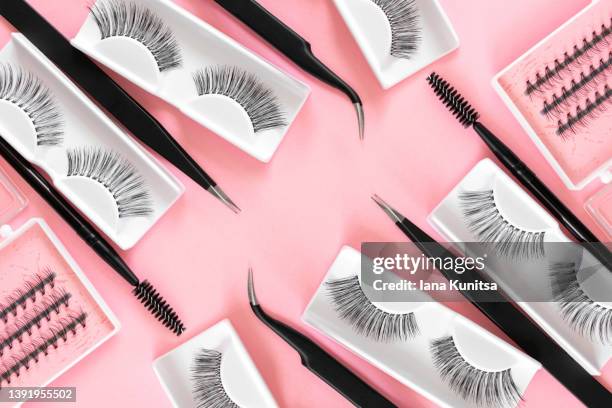 various tools for eyelash extensions on trendy pastel pink background. concept. fake eyelashes, tweezers and brush. makeup accessories. cosmetics. - wimpern stock-fotos und bilder