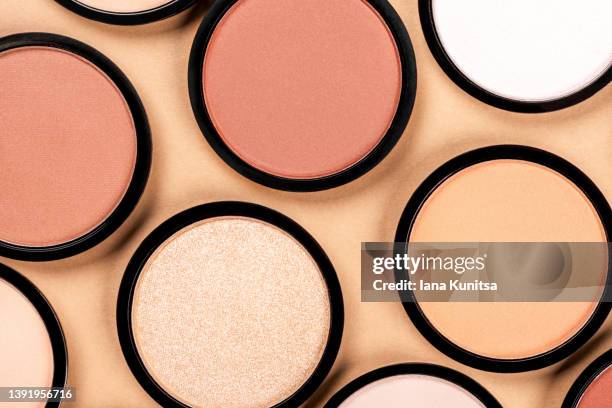compact face powder, blush, eye shadow on beige background. cosmetic products for makeup, skin care, contouring. top view. - blusher make up photos et images de collection