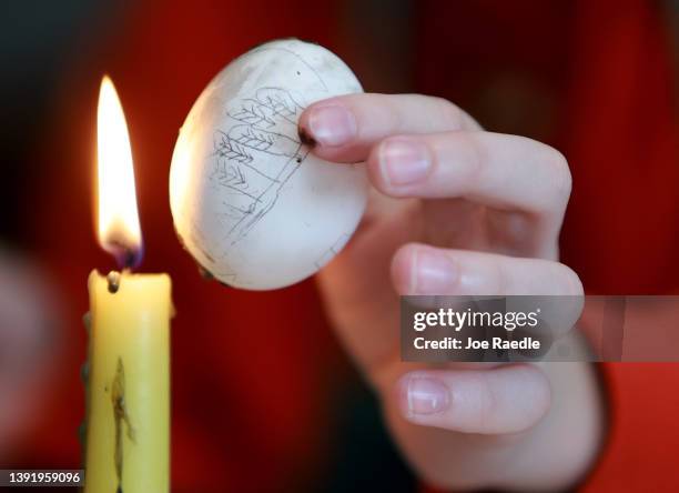 Candle is used to melt wax on an Easter egg as it is decorated on April 17, 2022 in Lviv, Ukraine. The egg was being decorated by a child who fled...