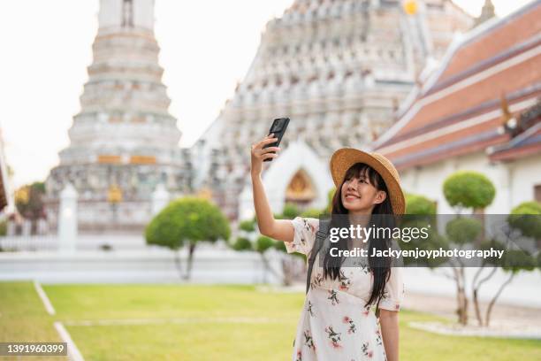 young asian traveler take a photo/selfie at wat pho and wat arun temple in bangkok, thailand enjoying the rich history of the famous place. - asian tourist bildbanksfoton och bilder