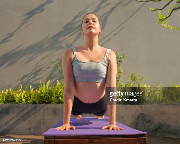 young woman practicing upward facing dog pose. - woman stretching sunset stock-fotos und bilder
