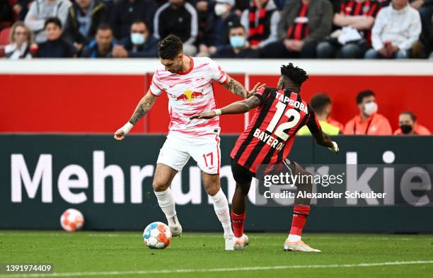 Dominik Szoboszlai of RB Leipzig is challenged by Edmond Tapsoba of Bayer 04 Leverkusen during the Bundesliga match between Bayer 04 Leverkusen and...