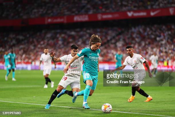 Luka Modric of Real Madrid passes the ball under pressure from Marcos Acuna of Sevilla FC during the LaLiga Santander match between Sevilla FC and...