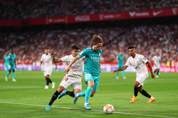 Luka Modric of Real Madrid passes the ball under pressure from Marcos Acuna of Sevilla FC during the LaLiga Santander match between Sevilla FC and...