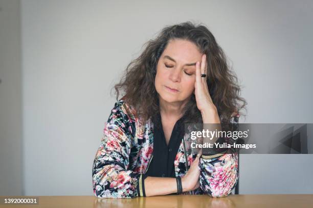 depressed or unwell pretty middle-aged woman - menopause stock-fotos und bilder