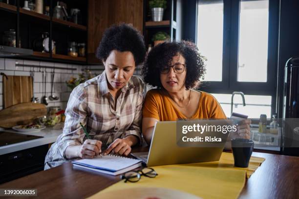 lesbian couple paying bills online - home budget stockfoto's en -beelden