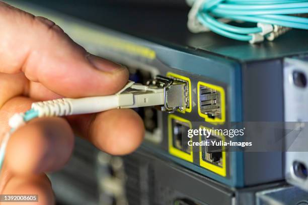 engineer ot technician withdrawing a lan or ethernet cable - enchufar fotografías e imágenes de stock