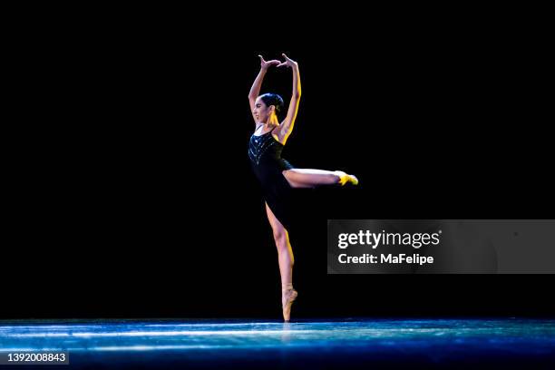 young girl performing neo-classic ballet wearing a black dress on a dark stage - solo performance stock pictures, royalty-free photos & images