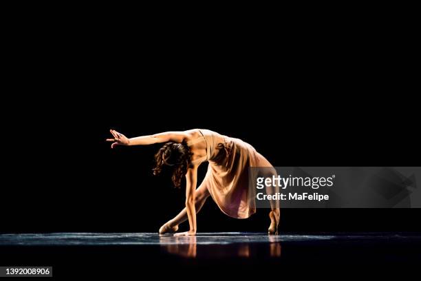 teenager girl performing contemporary dance on dark stage - dança contemporânea imagens e fotografias de stock