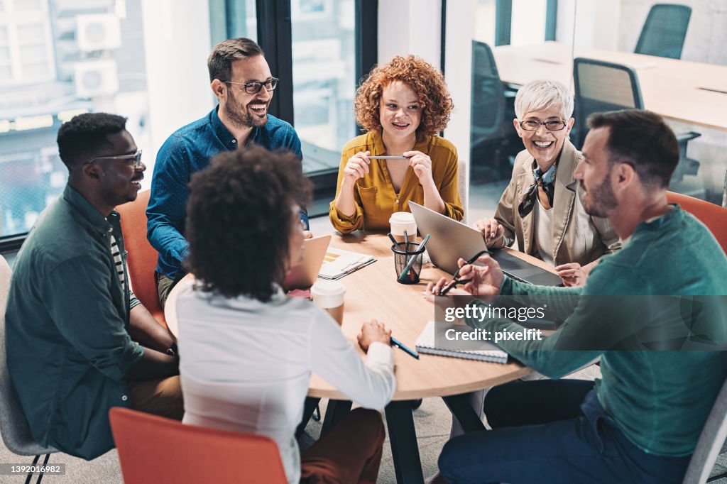 Mixed group of business people sitting around a table and talking