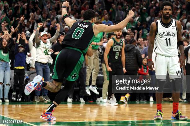 Jayson Tatum of the Boston Celtics celebrates the game winning basket as Kyrie Irving of the Brooklyn Nets looks on during the fourth quarter of...