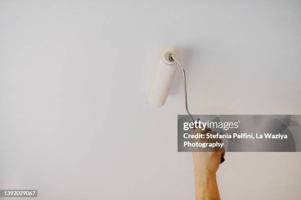 hand painting a ceiling with a paint roller. - holding paint roller stock pictures, royalty-free photos & images