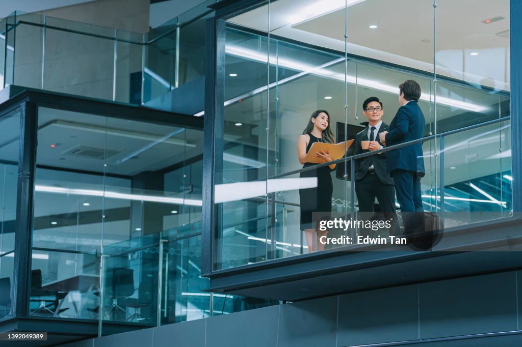 Bürogebäude Außenansicht durch das Fenster Chinesischer Geschäftsmann, der spät in der Nacht im Besprechungsraum arbeitet