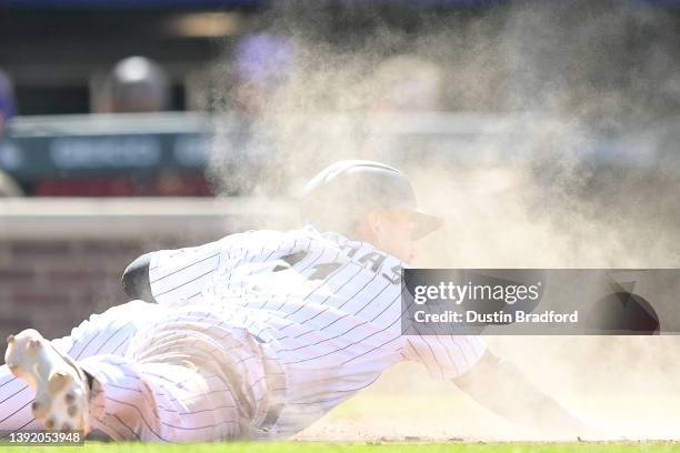 Jose Iglesias of the Colorado Rockies slides across home plate with a seventh inning run on a sacrifice fly against the Chicago Cubs at Coors Field...