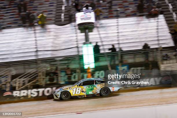 Kyle Busch, driver of the Mars Crunchy Cookie Toyota, crosses the finish line to win the NASCAR Cup Series Food City Dirt Race at Bristol Motor...