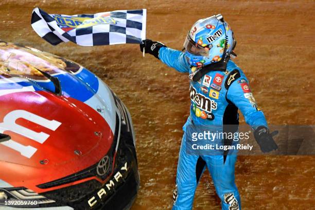 Kyle Busch, driver of the Mars Crunchy Cookie Toyota, celebrates with the checkered flag after winning the NASCAR Cup Series Food City Dirt Race at...