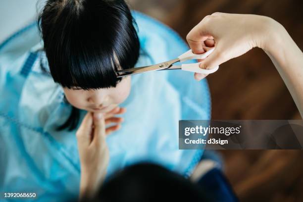overhead view of young asian mother cutting hair of her little daughter at home - bad bangs imagens e fotografias de stock