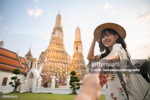 rear view of young beautiful woman holding her boyfriend' hand during travel at temple in bangkok. - wat arun tempel stock-fotos und bilder