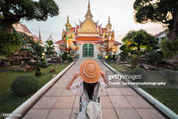 rear view of young asian woman stand and look at buddha temple during vacation trip in bangkok - bangkok landmark stock pictures, royalty-free photos & images