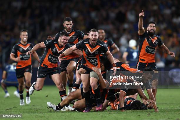 Jackson Hastings of the Tigers celebrates with team mates after kicking a field-goal to win the round six NRL match between the Parramatta Eels and...