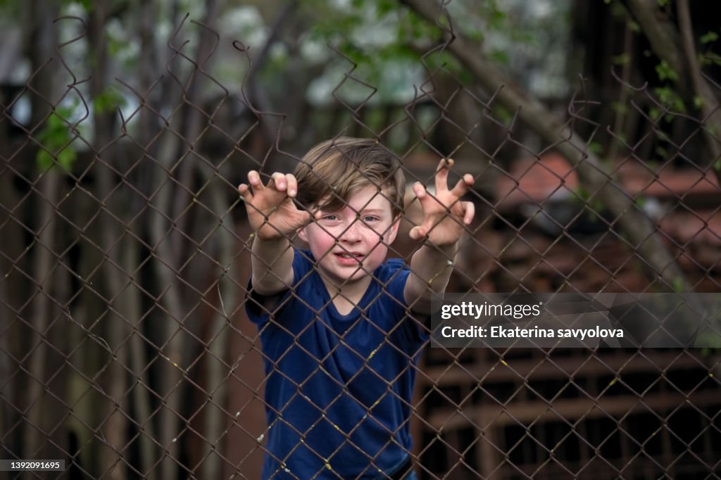 The boy behind the fence net.