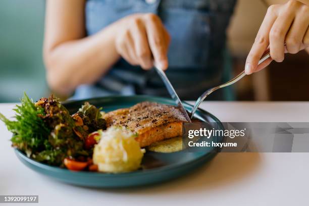 asian woman eating pan fried salmon in cafe - 健康飲食 個照片及圖片檔