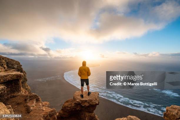 person contemplating sunset in lanzarote, spain - paesaggio spettacolare foto e immagini stock