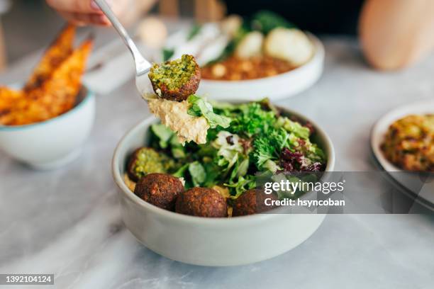 mujer comiendo falafel en un restaurante - vegan fotografías e imágenes de stock