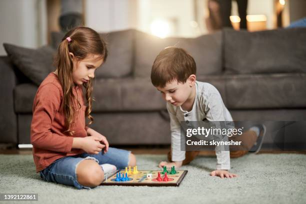 small kids playing ludo game on carpet at home. - little brother stock pictures, royalty-free photos & images