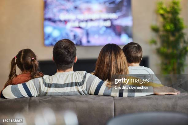 back view of a family watching tv at home. - boy at television stockfoto's en -beelden