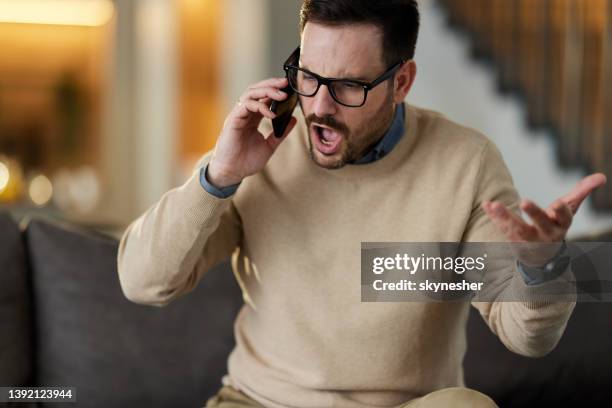 angry man talking on cell phone at home. - shouting phone stock pictures, royalty-free photos & images