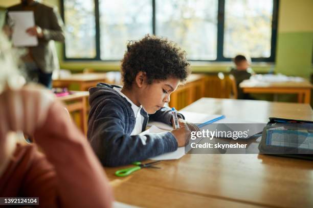black schoolboy writing on a class at elementary school. - class rules stock pictures, royalty-free photos & images
