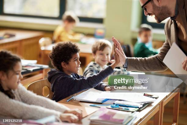 happy teacher and schoolboy giving each other high-five on a class. - schoolhoofd stockfoto's en -beelden