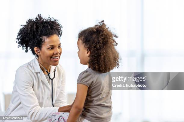 female doctor checks girl's heartbeat - pediatric imagens e fotografias de stock