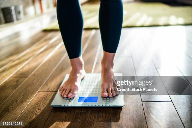 la femmina sta controllando il suo peso sulla bilancia - weight scale foto e immagini stock
