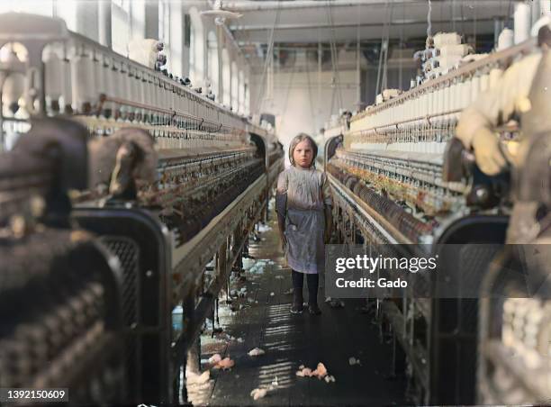 Child laborer stands among machinery in a cotton mill in Newbery, South Carolina, 1908. Courtesy Lewis Hine. Note: Image has been digitally colorized...