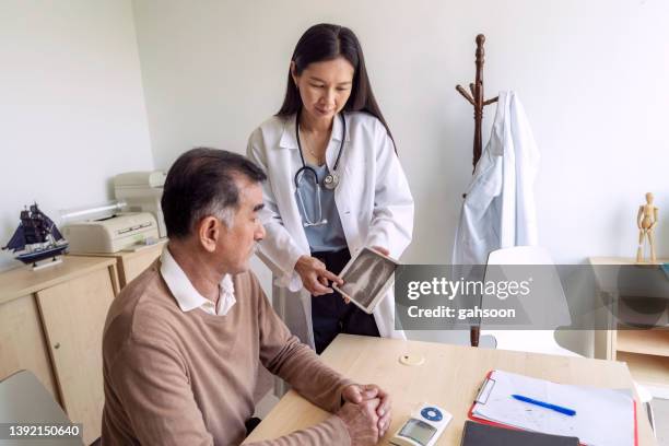 doctor discussing medical test results with patient using digital tablet - colonoscopy stock pictures, royalty-free photos & images