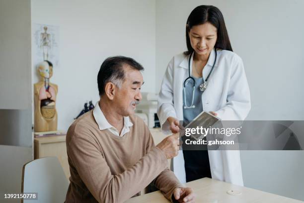 médico discutindo resultados de testes médicos com paciente usando tablet digital - colonoscopy - fotografias e filmes do acervo