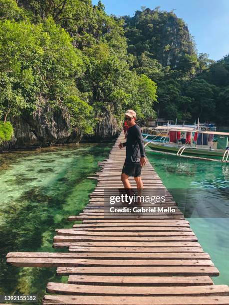 tourist looking behind while walking in the wood bridge - palawan island stock pictures, royalty-free photos & images