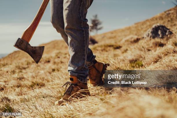hombre sosteniendo un hacha caminando solo por la colina en un día soleado. - hacha pequeña fotografías e imágenes de stock