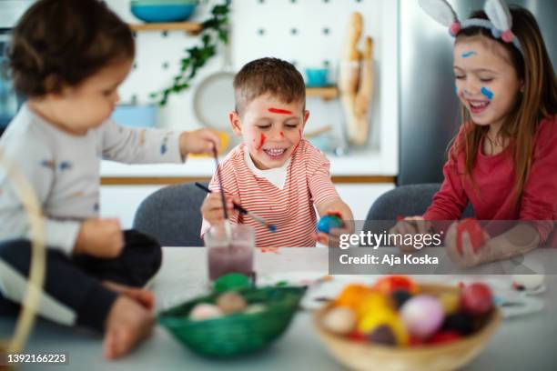 siblings painting easter eggs together. - dirty easter stock pictures, royalty-free photos & images